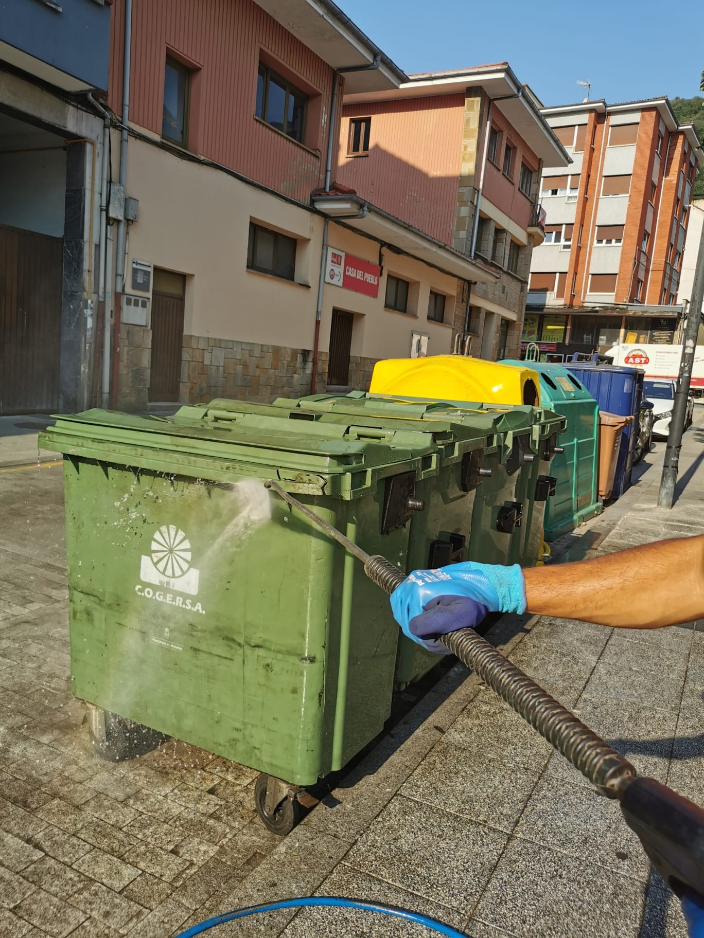 Operario limpiando una batería de contenedores con agua a presión.