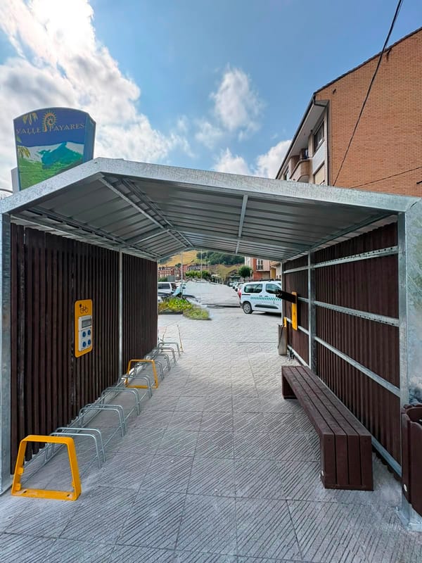 Refugio cubierto con aparcabicicletas y banco en un área de servicio para ciclistas